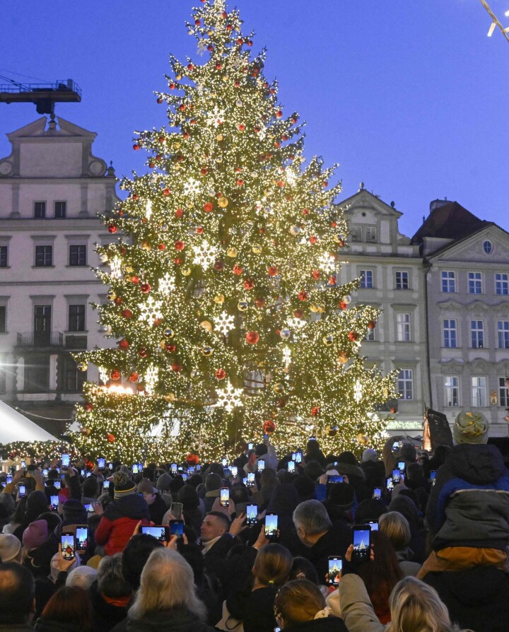 People take photos of the Christmas tree at the Christmas market at Old Town Square in Prague on November 30, 2024. (Photo by Michal Cizek / AFP)