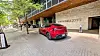 Rød Tesla Model Y parkert foran JW Marriott-hotell ved fortauskant