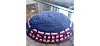 Blue crocheted kippah with red and white lettering resting on a glass table
