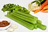 Celery stalks with carrots, parsley, garlic, and seasoning on a white background.