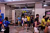 Crowd of soccer fans in jerseys walks through a station concourse toward a train entrance.