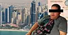 Man in een grijs T-shirt met opvallende print voor de skyline van Dubai.