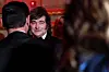 Javier Milei faces the camera while greeting attendees at a crowded indoor gala.