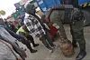 Un agente uniformado y varias personas rodean una garrafa de gas en una calle comercial concurrida.