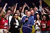 Lula sostiene un micrófono y una bandera de Brasil mientras celebra rodeado de simpatizantes.