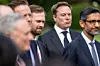 Elon Musk (left) and Sundar Pichai (right) among suited men outdoors, with the central man in focus